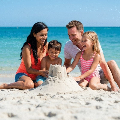 Family with two children building a sandcastle on a sunny Southwest Florida beach